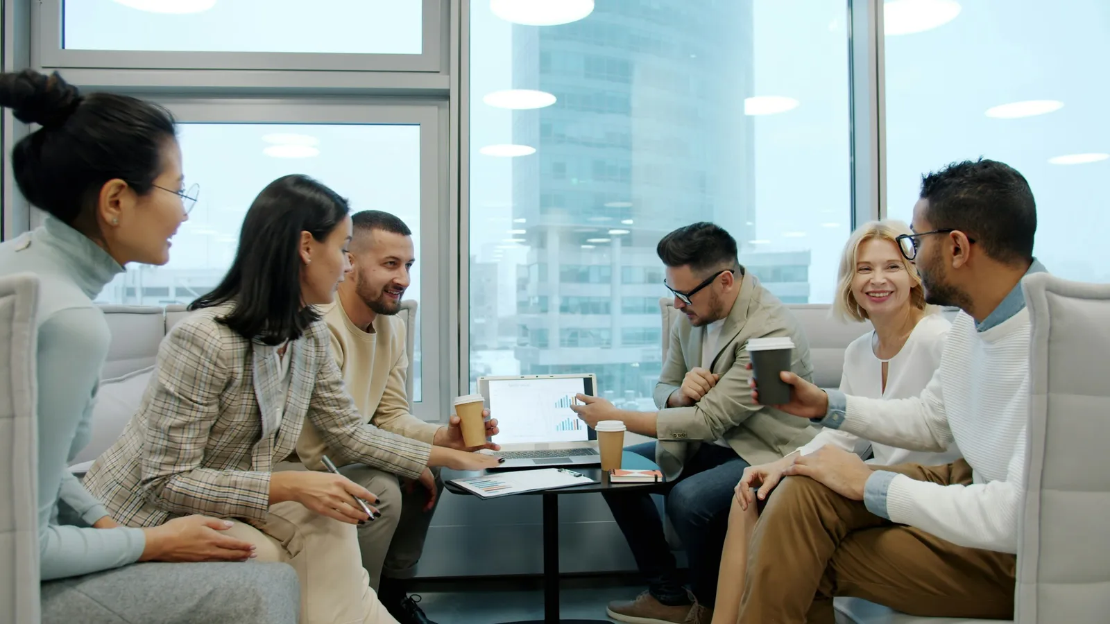 A team gathered around a laptop in a bright workspace